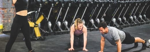 A coach assisting clients during small group personal training in Fairfax, ensuring proper form and technique.